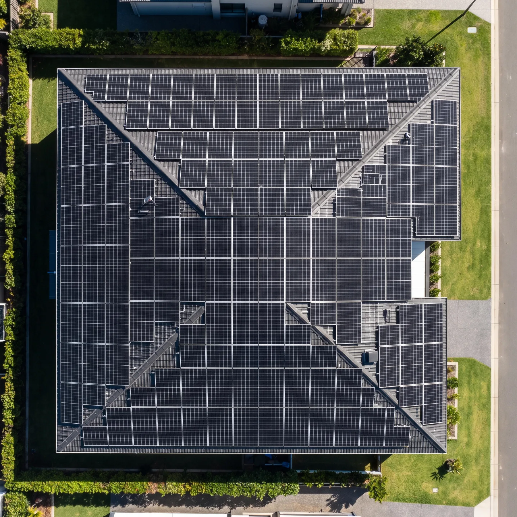 Top-down view of a residential roof covered with a geometric grid of solar panels